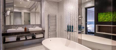 Un baño moderno con una bañera independiente grande, dos lavamanos y un espejo amplio.
