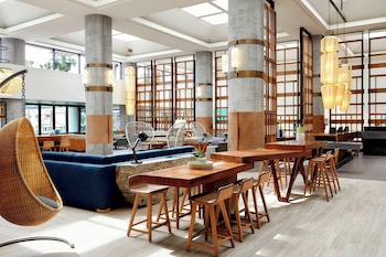 A modern interior with a central dining area, wooden partitions, and a view through a glass door. at Westdrift Manhattan Beach, Autograph Collection by Marriott