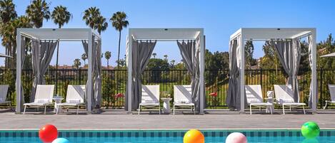 A pool area with lounge chairs, a pool, and a pergola structure.