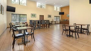 A spacious dining area with multiple tables and chairs, large windows, and a flat-screen TV mounted on the wall. - Best Western Heritage Inn - Chico (Chico)