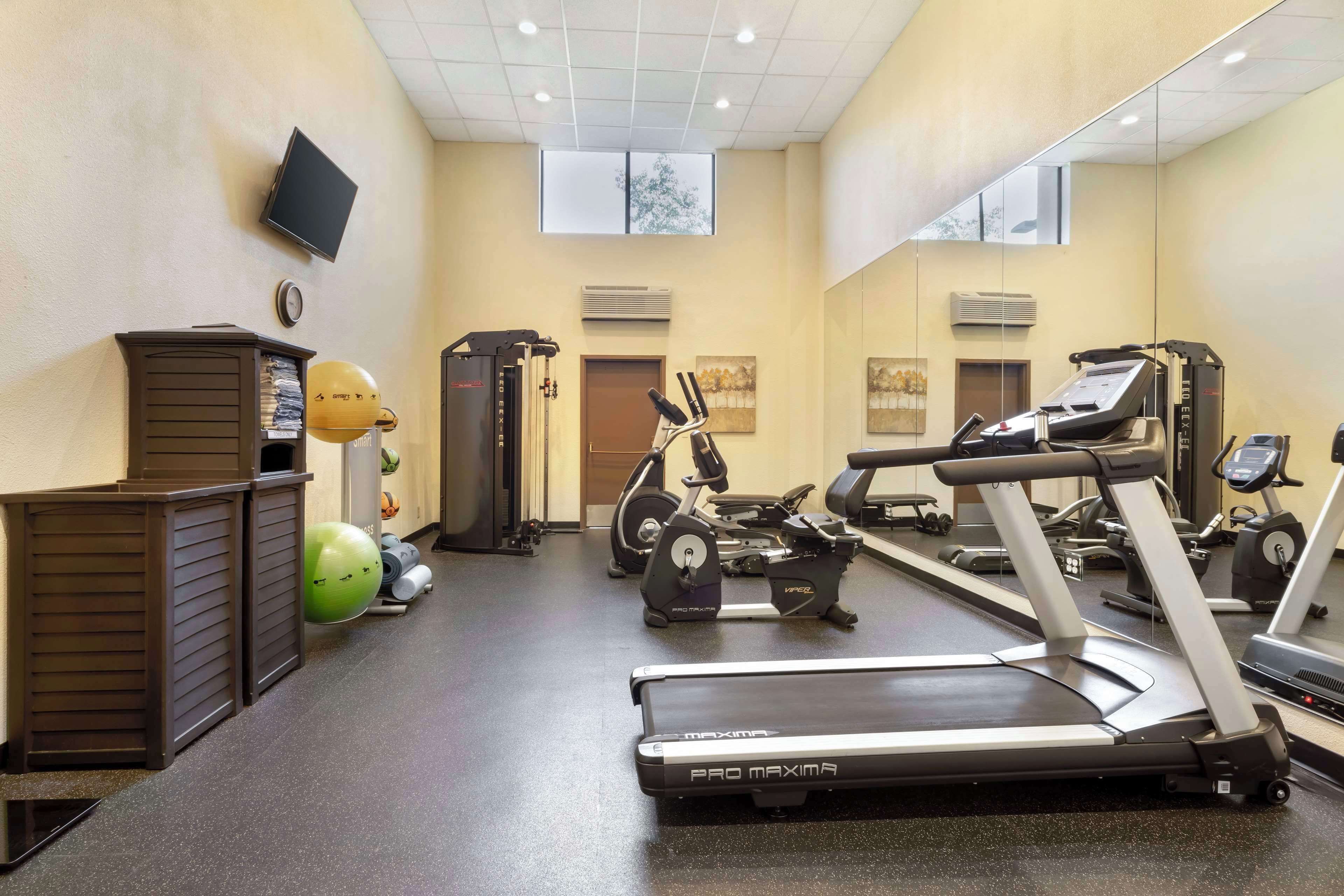 A gym with treadmills, exercise bikes, and a mirrored wall.