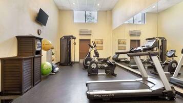 A gym with treadmills, exercise bikes, and a mirrored wall.