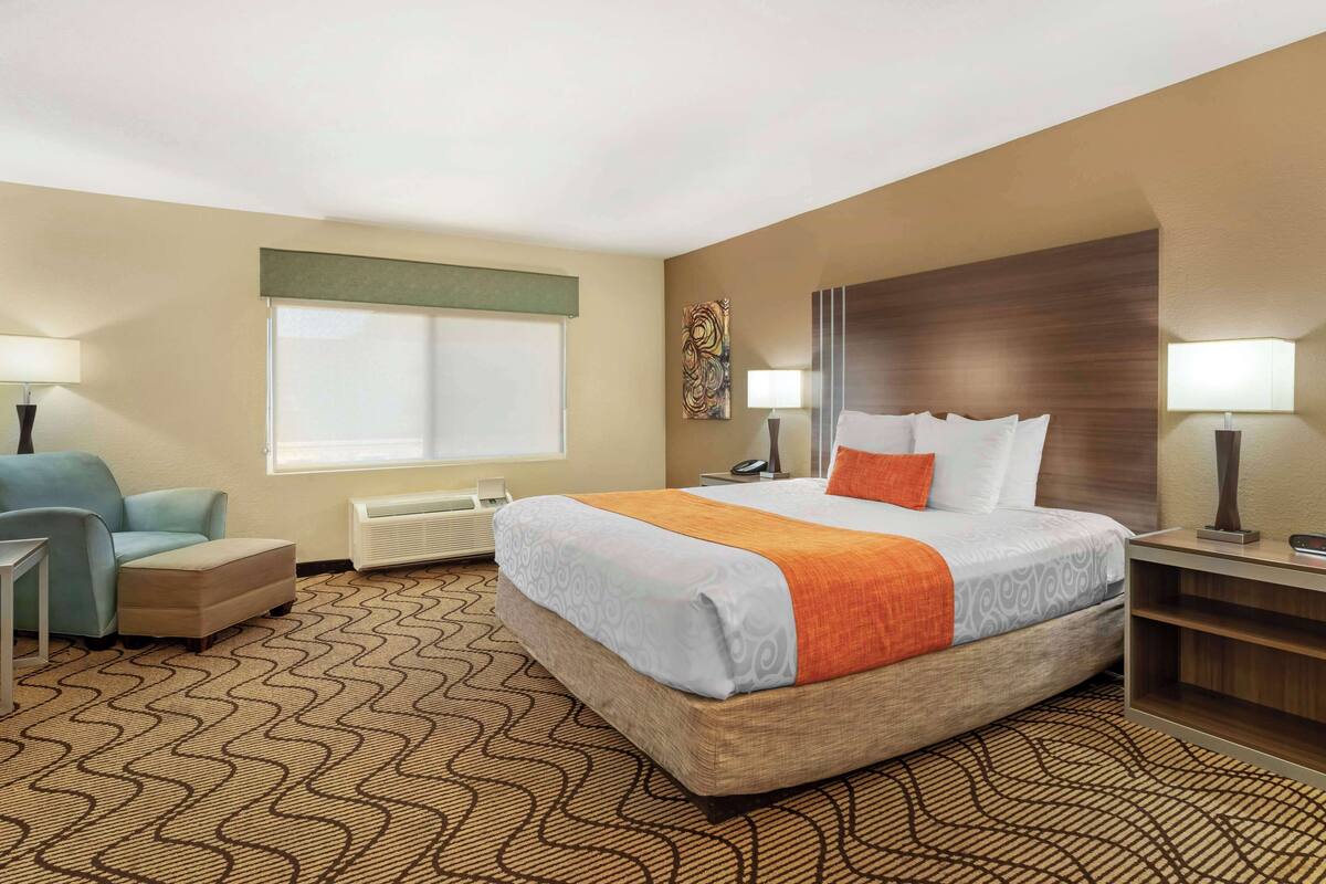 A hotel room with a large bed, a chair, a desk, and a window.