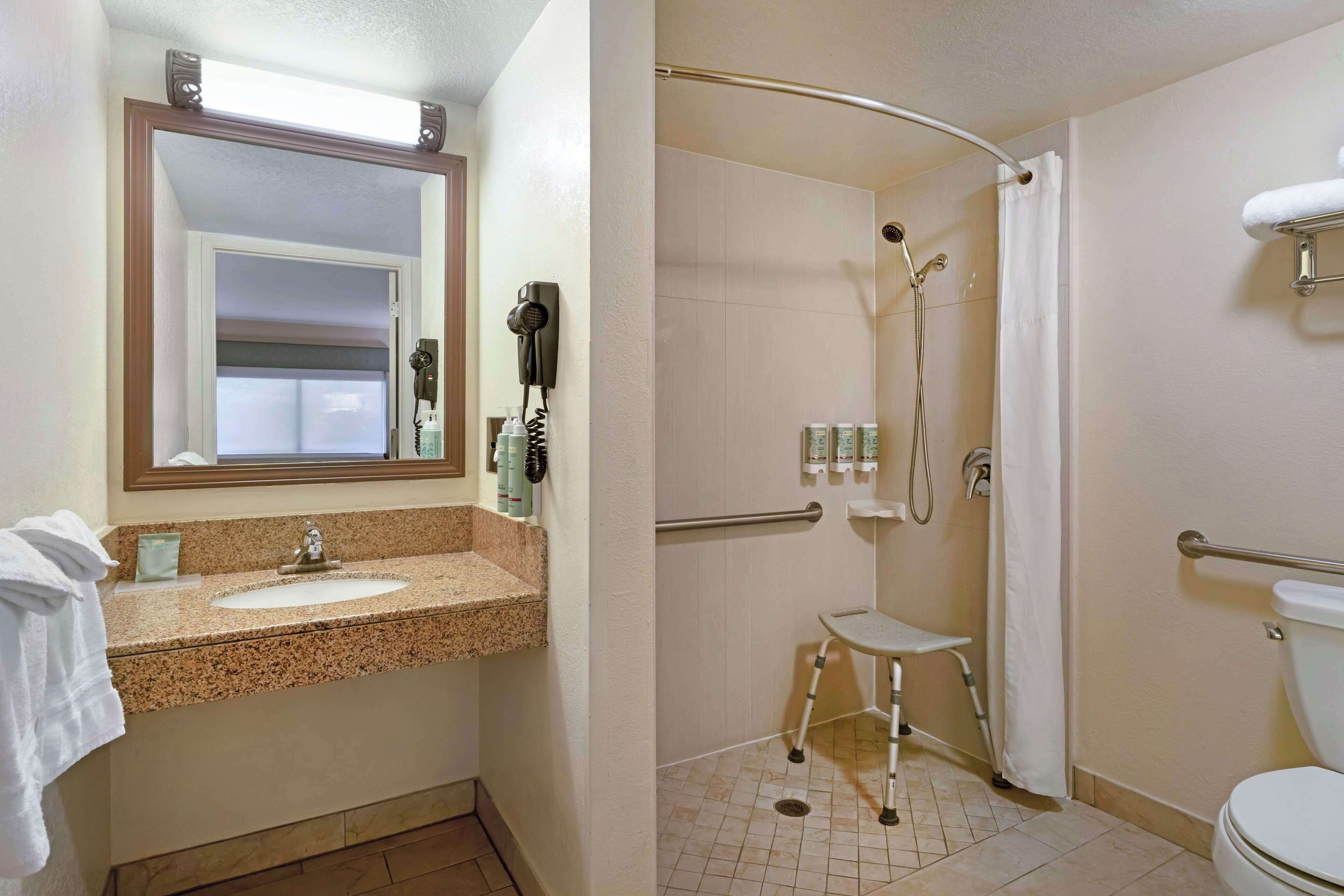 A bathroom with a sink, mirror, and shower.
