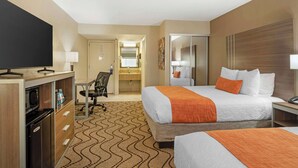 A hotel room with two beds, a desk with a television, a refrigerator, a chair, and a bathroom visible in the background. - Best Western Heritage Inn - Chico (Chico)