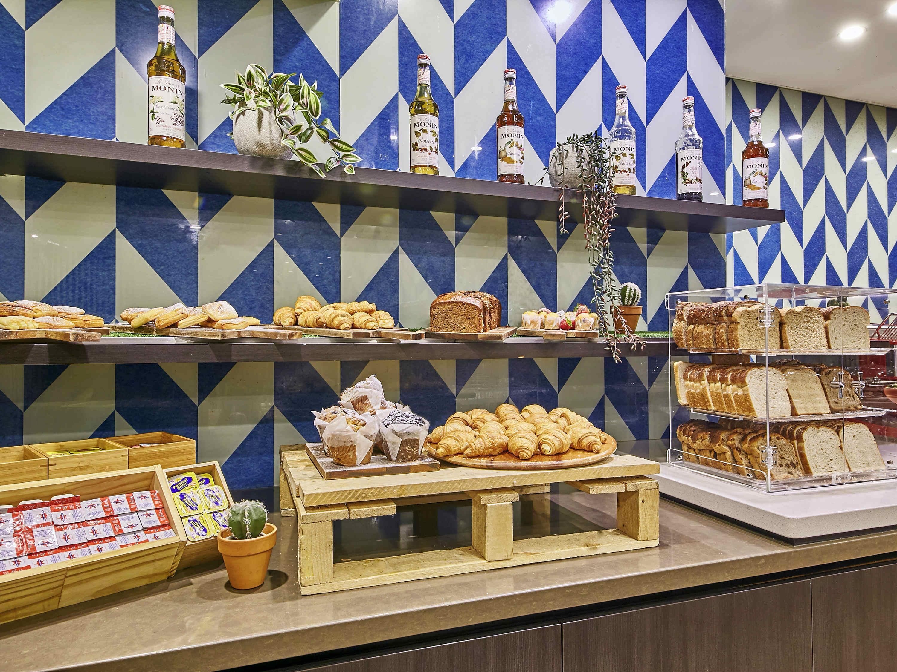 A bakery display with pastries, bread, and Monin syrup bottles.