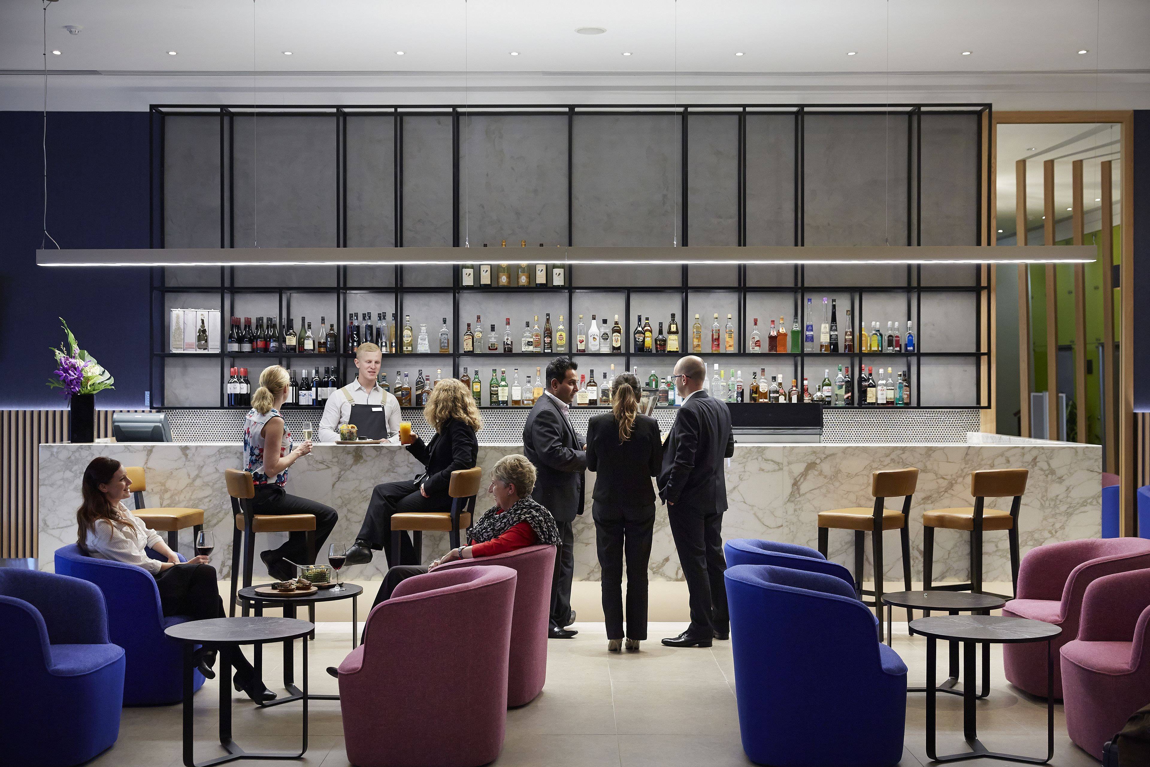 A modern bar area with seating and a well-stocked liquor display.