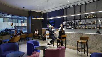 A modern bar area with seating and a wine display.