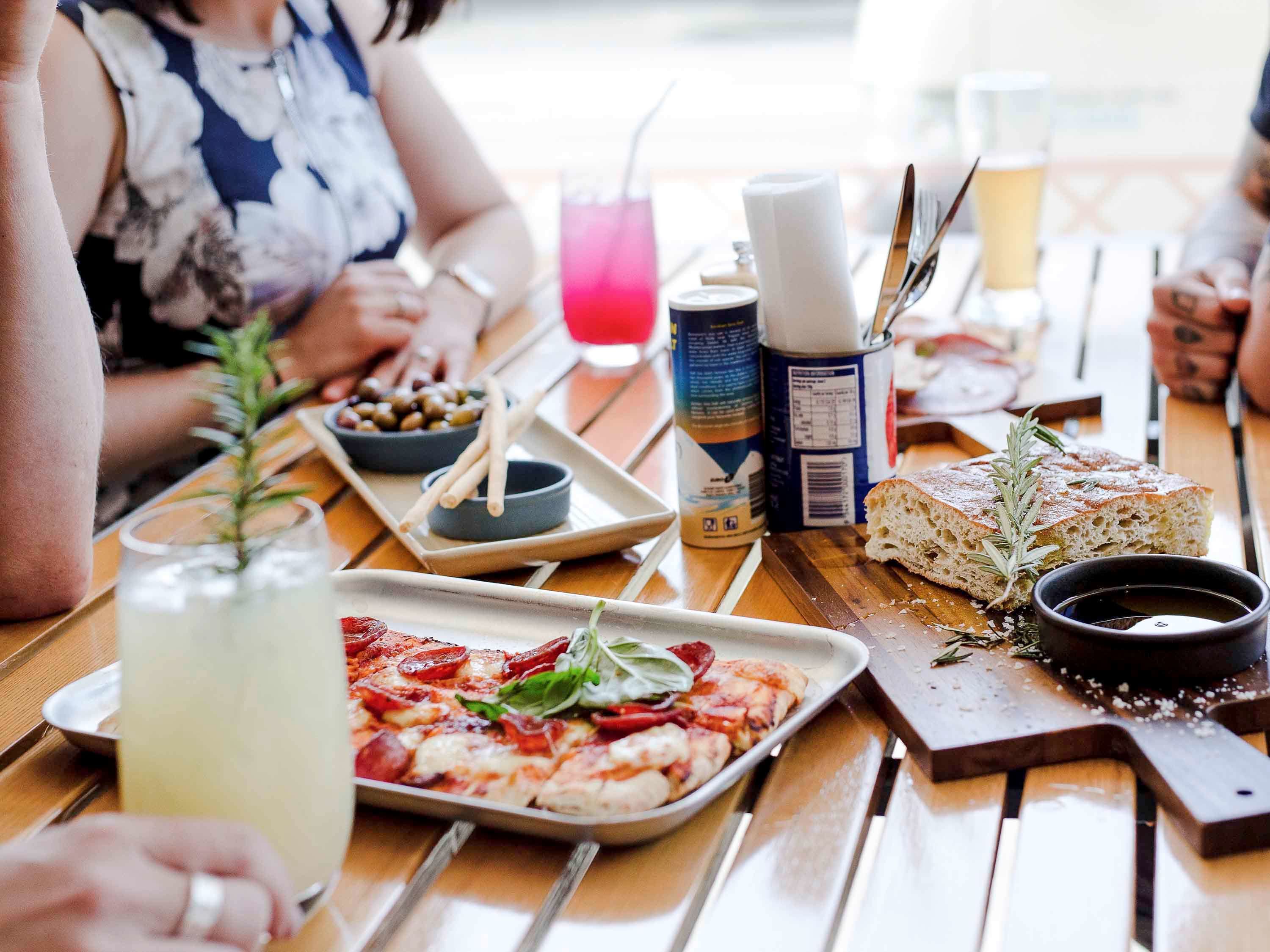 Taula amb pizza, una beguda i condiments.