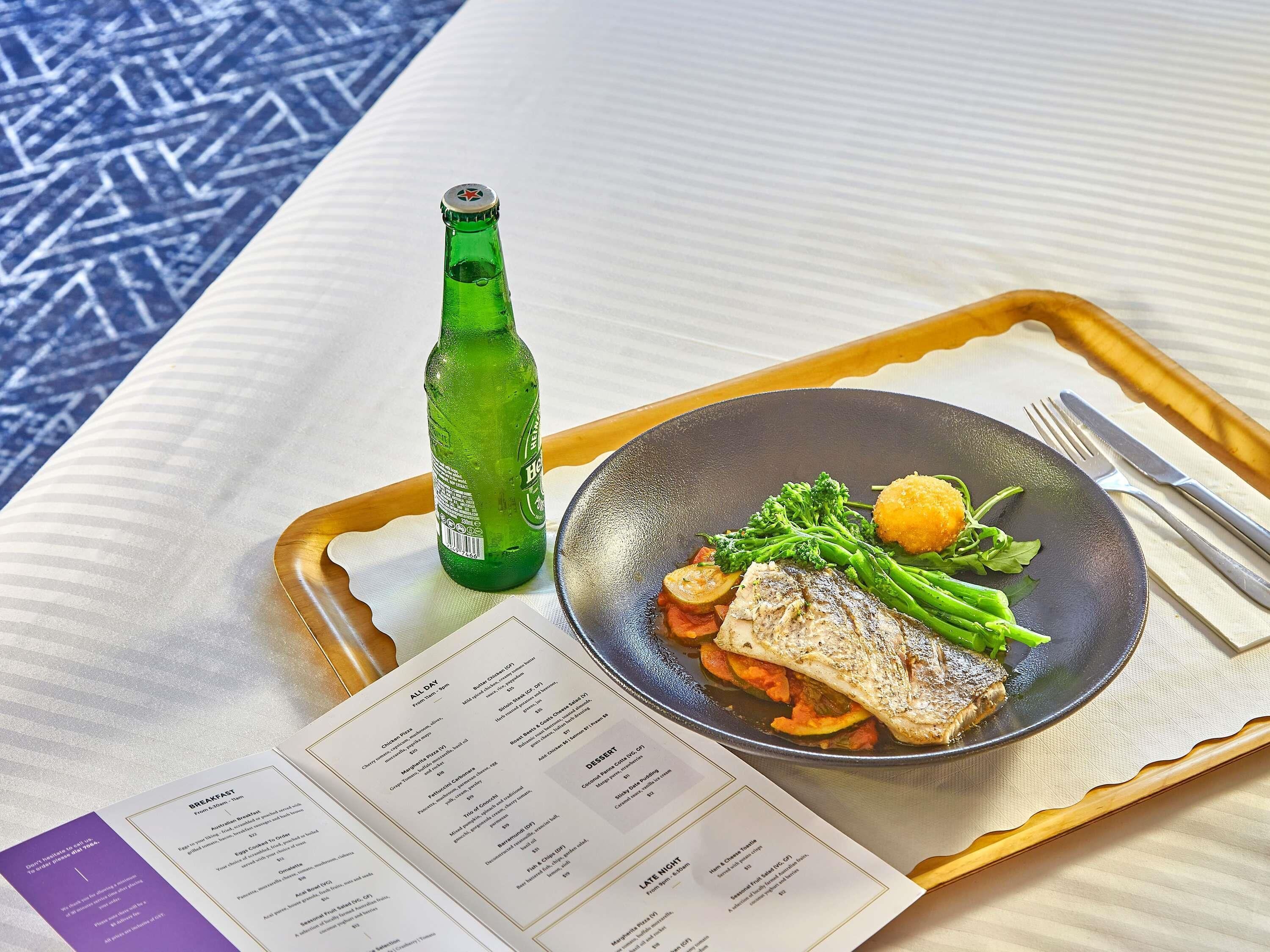 Eine Serviettenwagen mit einem Fischgericht, Gemüse und einer grünen Flasche, begleitet von einer Speisekarte.