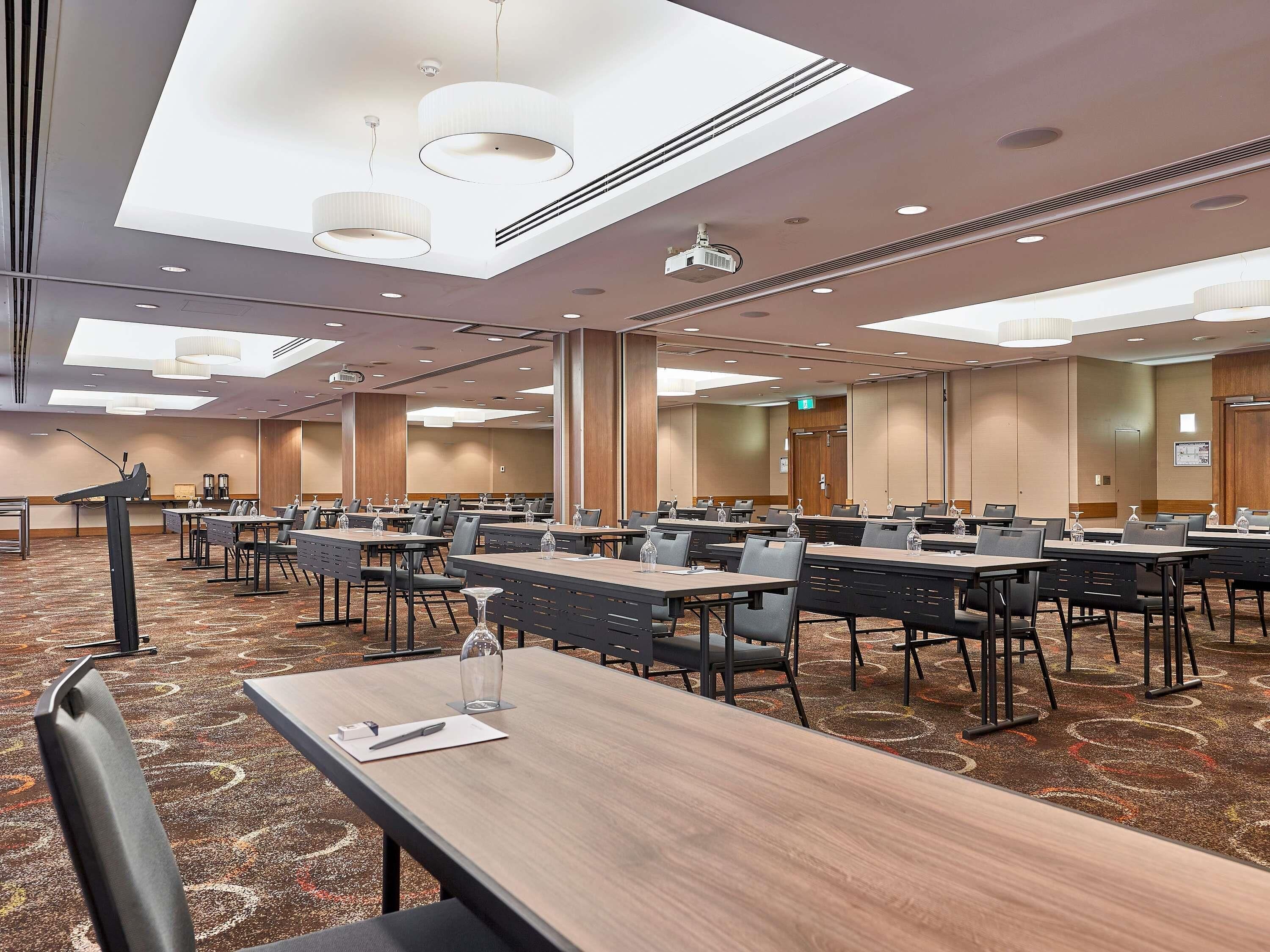 A conference room with multiple tables, chairs, and a podium.