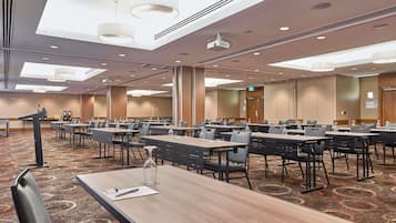A conference room with multiple tables, chairs, and a podium.
