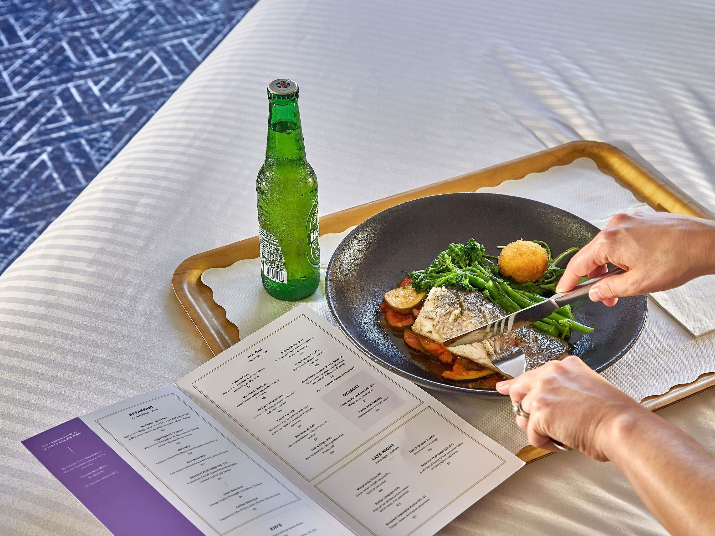 Eine Essschale mit Fischgericht, Gemüse und einer grünen Flasche auf einem Tisch mit einer Speisekarte.