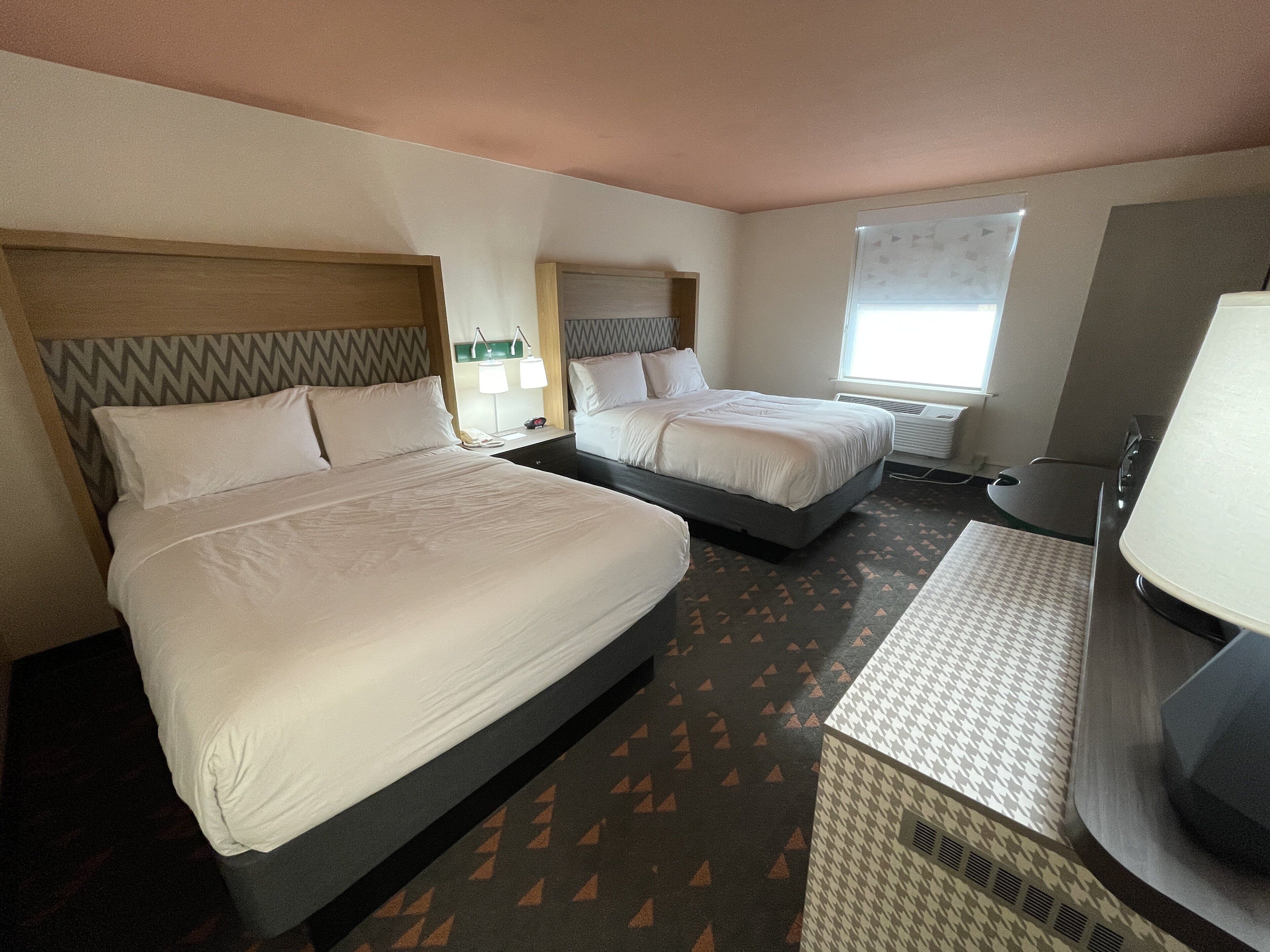 Una habitación de hotel con dos camas, un escritorio y una ventana.