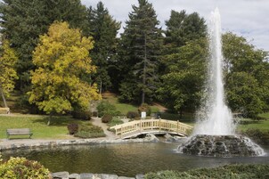 Ein Park mit einem Springbrunnen, einer Holzbrücke und einer Bank.