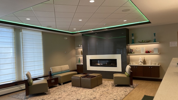 A modern living room with a fireplace, a sofa set, a coffee table, and a decorative shelf. - Holiday Inn Bangor by IHG (Bangor)