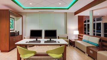 A modern office space with two desks, chairs, a sofa, and a lamp.