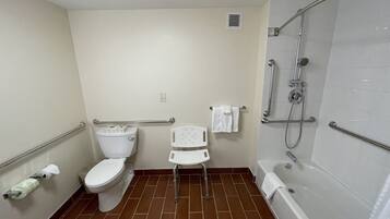 A bathroom with a toilet, a shower with grab bars, a white sink, and a white bathtub.