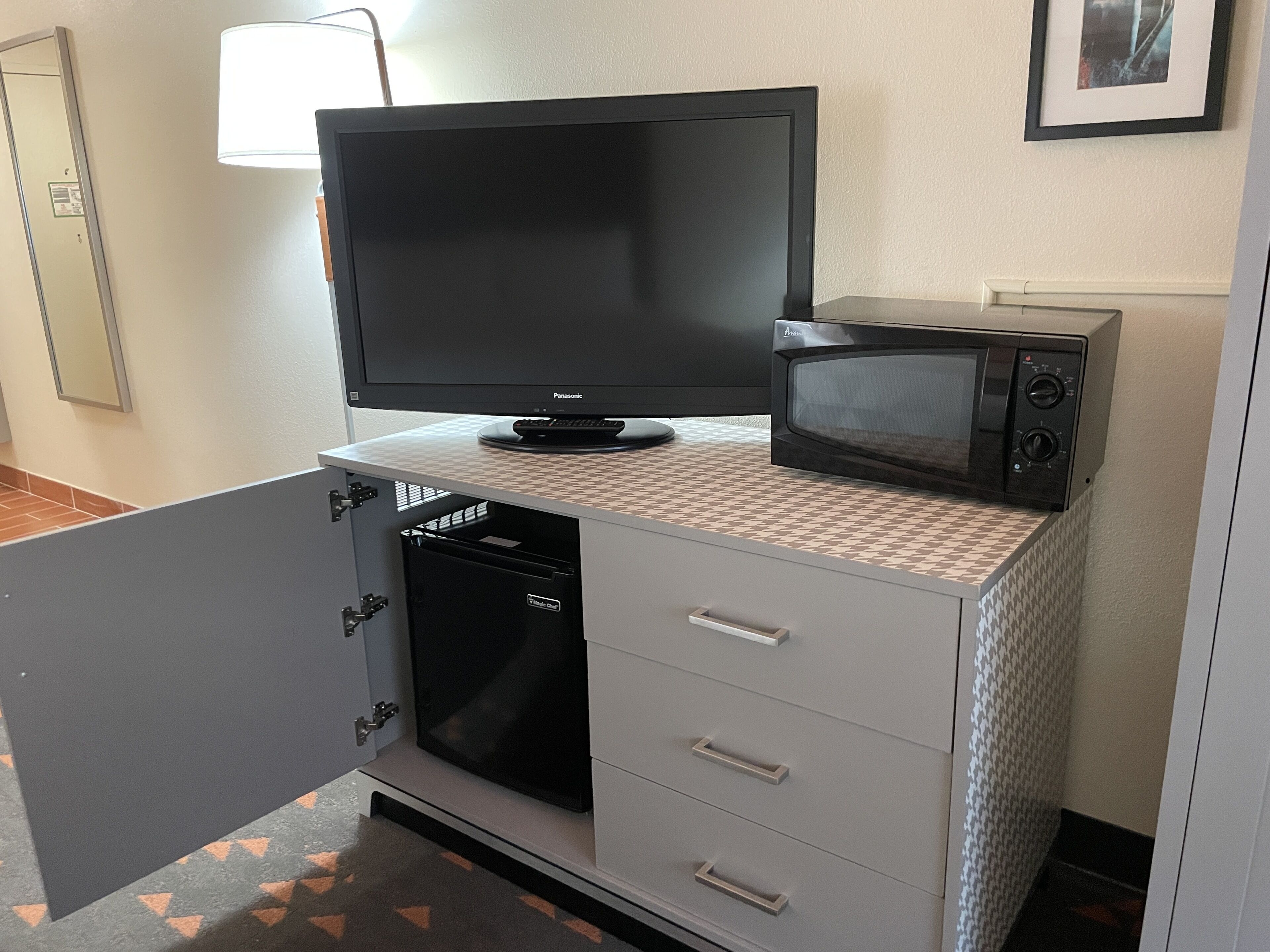 A kitchenette with a flat-screen TV, microwave, and a small refrigerator.