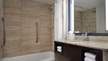 A modern bathroom with a bathtub, a shower with a handheld showerhead, a vanity with a sink, and a mirror.