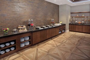 Un buffet avec différents stands de nourriture, un mur en briques et un plancher en bois à motifs.