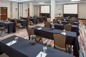 Una sala de conferencias con varias mesas, sillas y una pantalla grande.