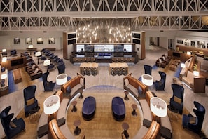 Un hall d’entrée spacieux doté d’un bar central, de plusieurs espaces de détente et d’un plafond haut avec un design moderne.