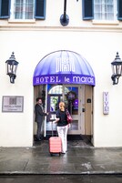 La entrada del HOTEL le marais, con un toldo azul, una señal y un adorno de bienvenida.
