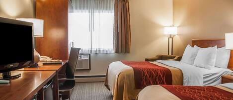 Habitación de hotel con dos camas, un escritorio con televisor, una silla, una lámpara de escritorio y una ventana con cortinas.