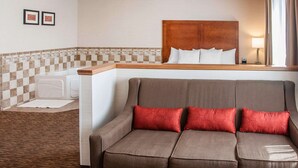 Une chambre d’hôtel avec un canapé marron, une tête de lit en bois et un pare-feu en carreaux.