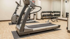 Une salle de sport équipée de tapis de course, d’un vélo d’appartement et d’un porte-haltères.