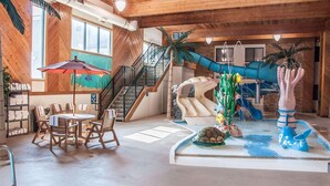Un grand espace intérieur doté d’un plancher en bois, d’une table à manger avec des chaises, d’un escalier et d’un toboggan.