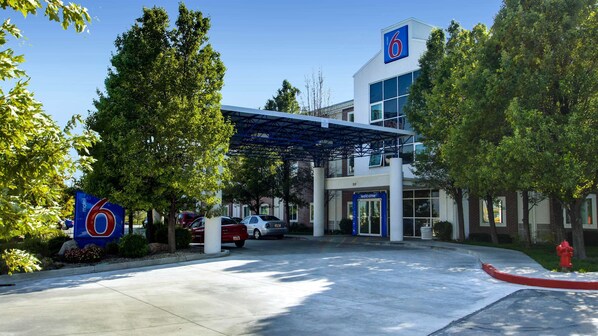 A motel with a large '6' sign, a covered entrance, and a fire hydrant.