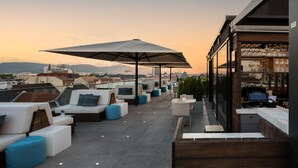 A rooftop terrace with seating, a bar area, and a view of the cityscape. - Garner Hotel Klagenfurt - Moser Verdino (Klagenfurt am Woerthersee)
