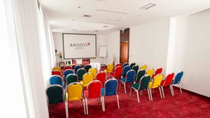 A conference room with rows of colorful chairs, a whiteboard, and a projector screen displaying "ARCOTEL HOTELS". - Garner Hotel Klagenfurt - Moser Verdino (Klagenfurt am Woerthersee)