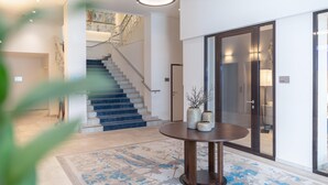 A modern interior with a staircase, a round table with vases, and a glass door labeled "Lounge". - Garner Hotel Klagenfurt - Moser Verdino (Klagenfurt am Woerthersee)