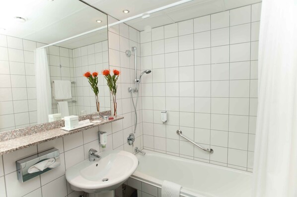 A modern bathroom with a white sink, mirror, and shower.