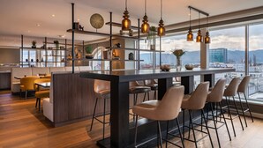 A modern kitchen with a central island, bar stools, and pendant lighting. - Garner Hotel Klagenfurt - Moser Verdino (Klagenfurt am Woerthersee)