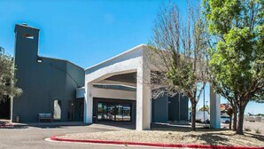 A modern building with a curved facade, large glass entrance, and a covered outdoor area. - Pan American Inn & Suites (Albuquerque)