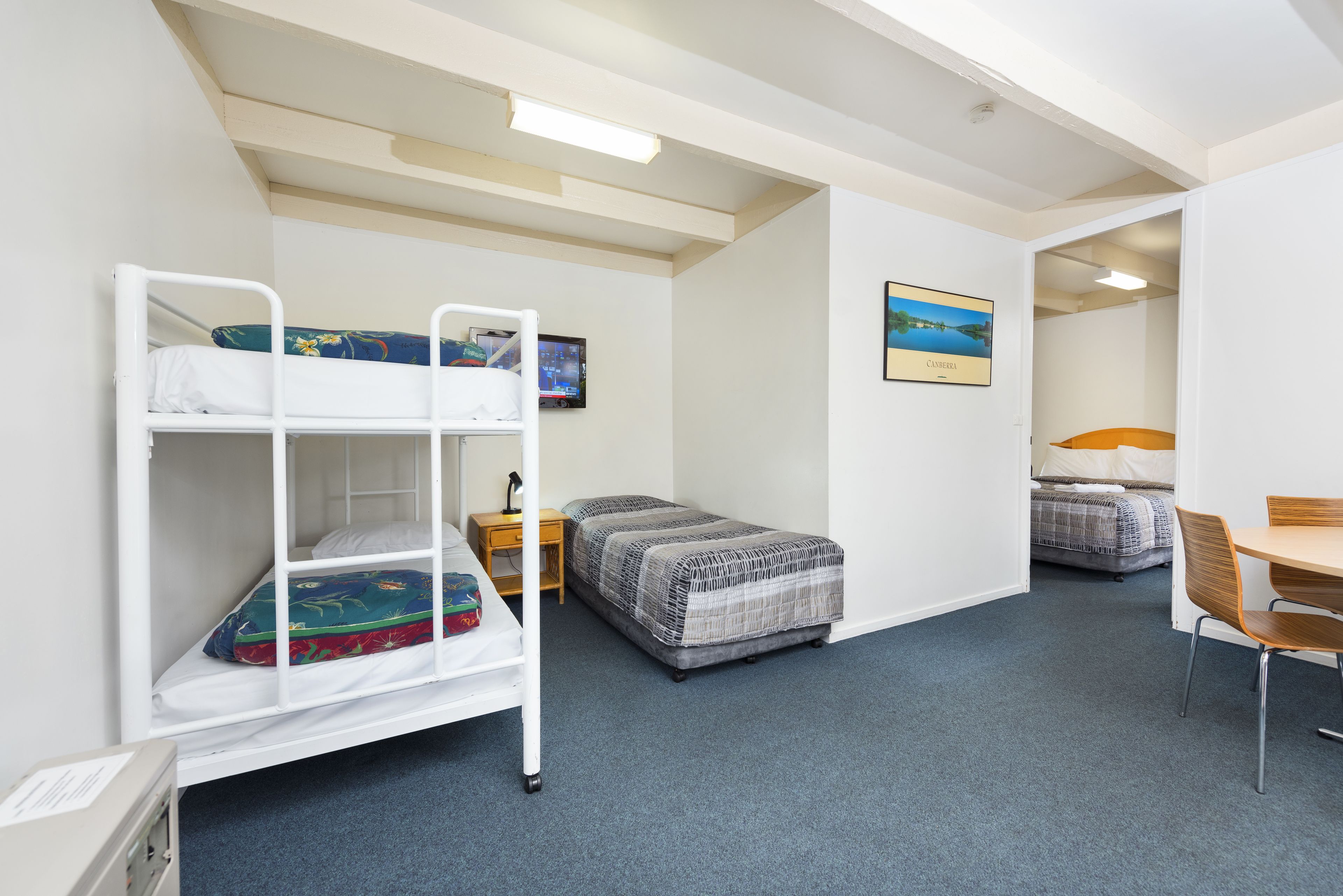 A dormitory room with bunk beds, a desk, and a chair.