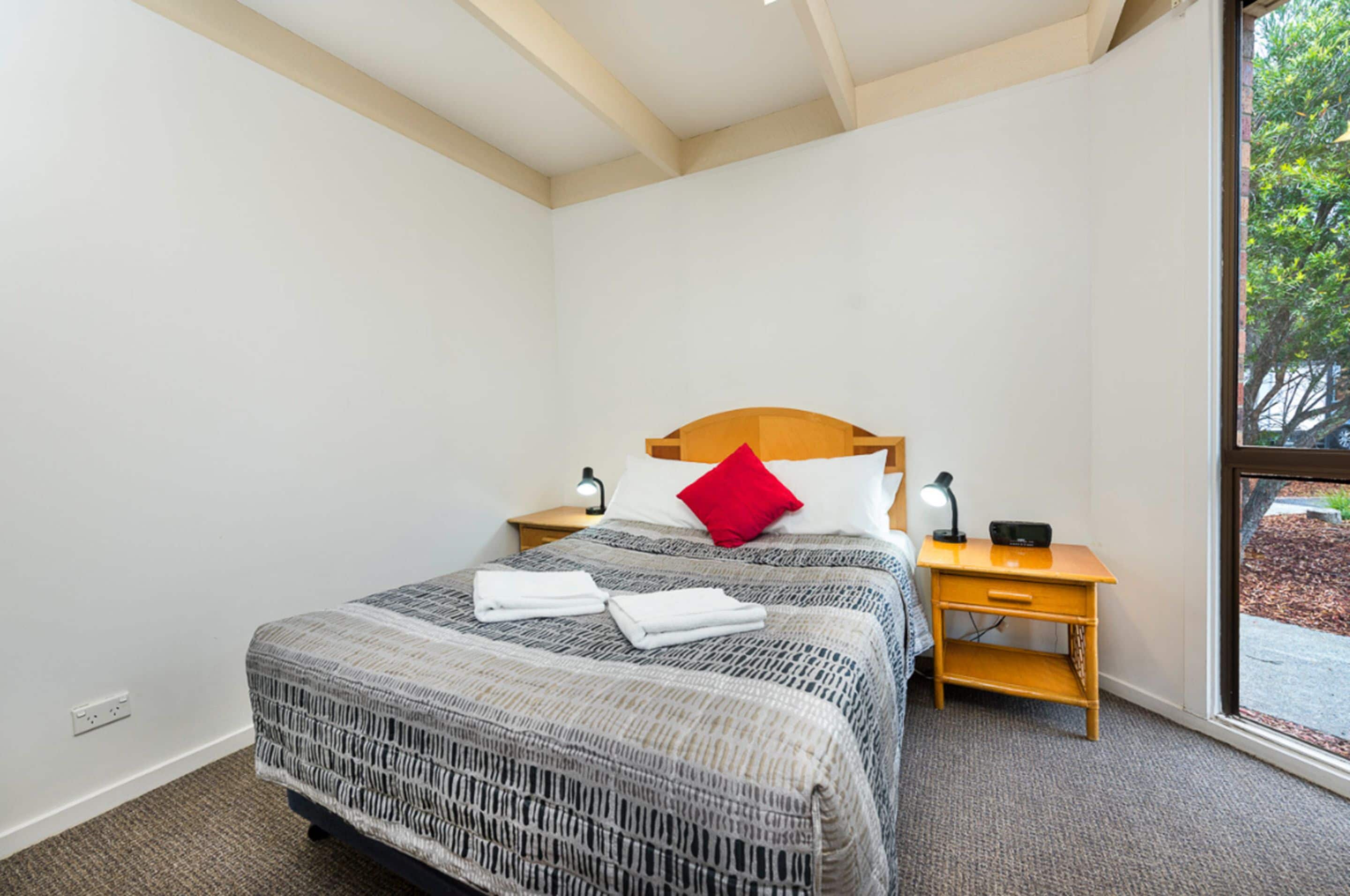Ein Schlafzimmer mit einem Bett, Nachttischen und einem Fenster.