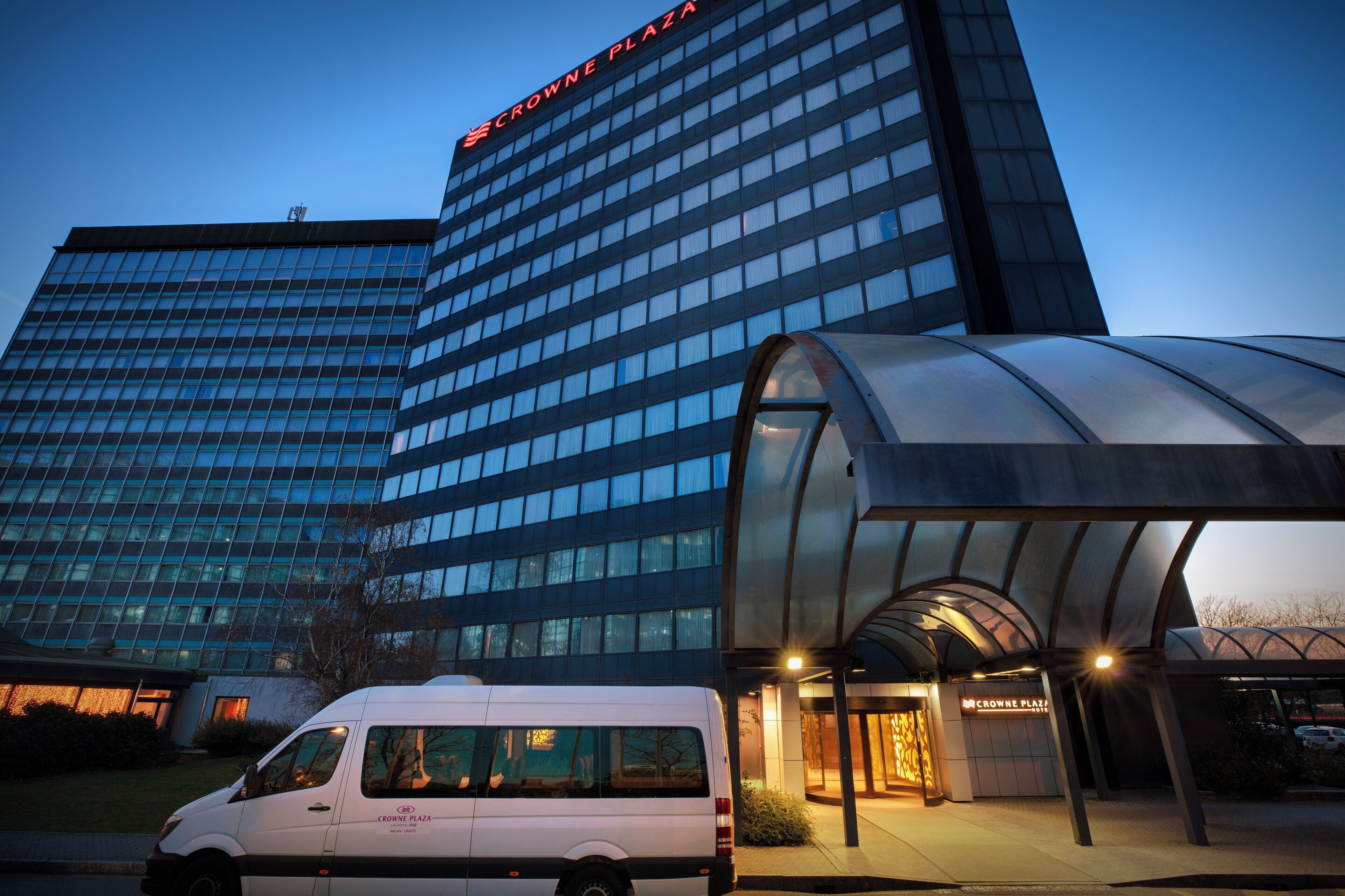 Un hotel con fachada moderna de vidrio y acceso cubierto.