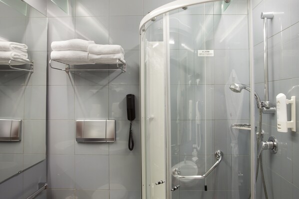 A modern bathroom with a glass-enclosed shower, a towel rack, a phone, and a soap dispenser.