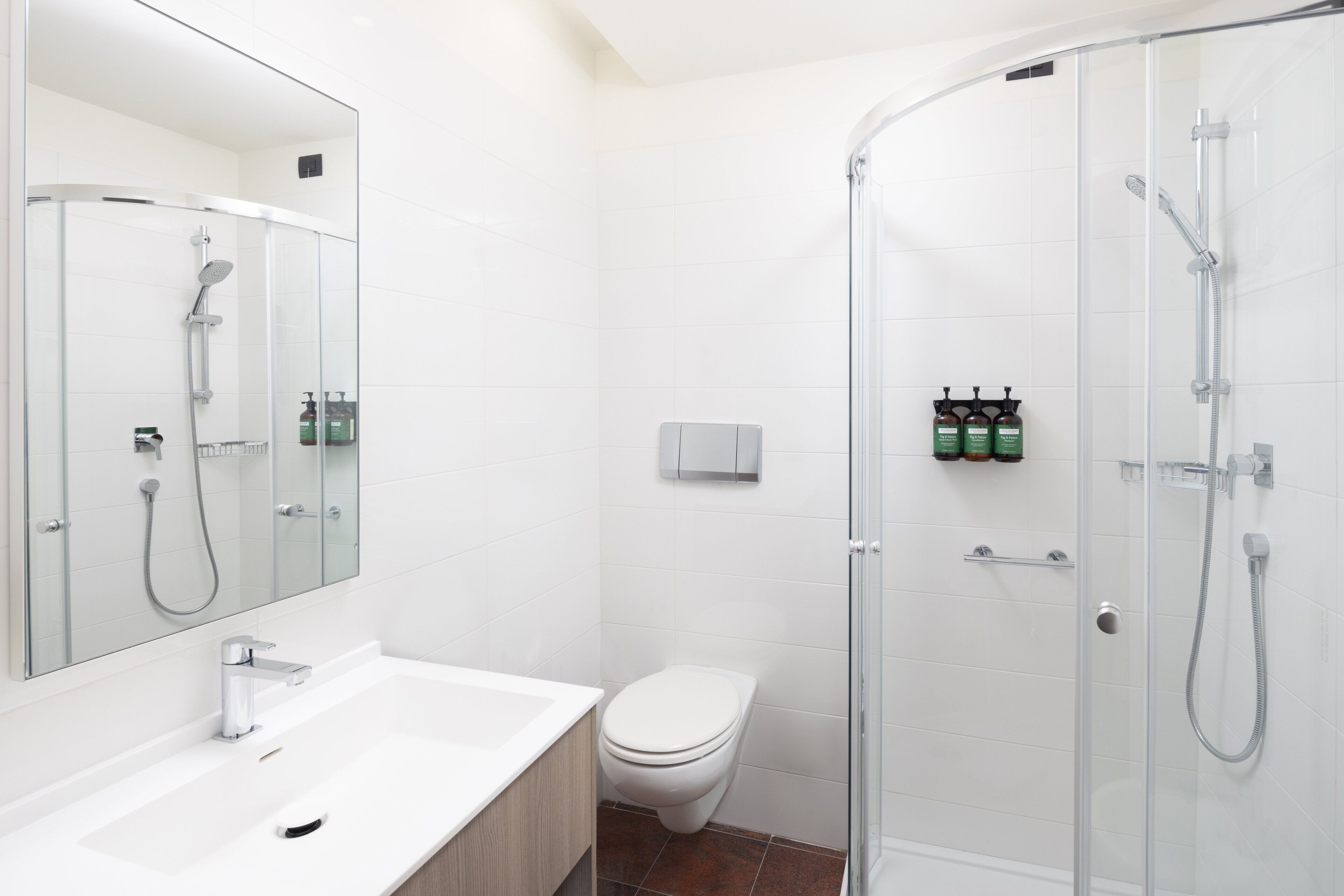 Une salle de bain moderne avec une douche à parois de verre, un lavabo blanc et des toilettes.