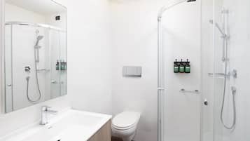 Une salle de bain moderne avec une douche à parois de verre, un lavabo blanc et des toilettes.