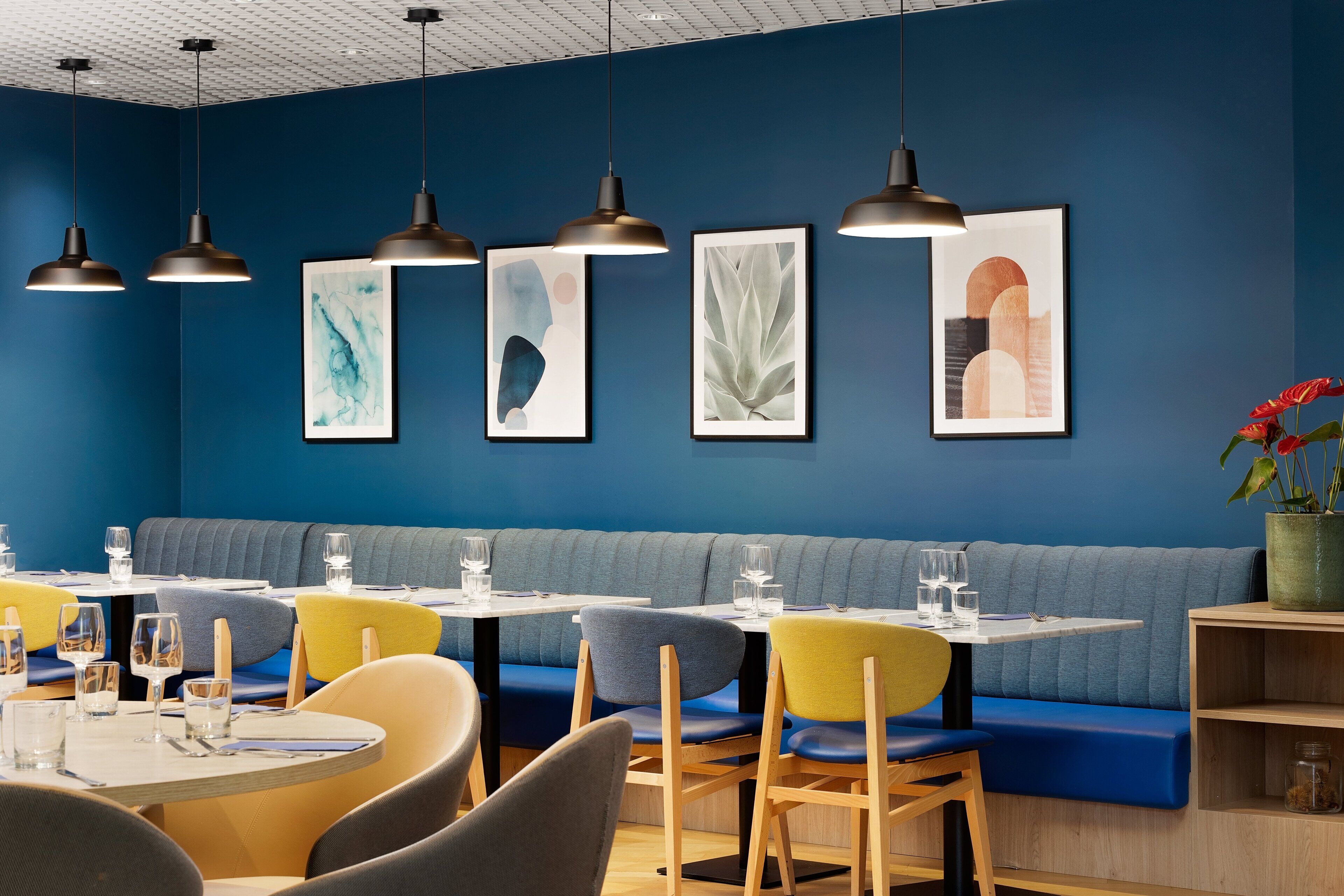 A restaurant interior with blue walls, multiple seating areas, and artwork on the walls.
