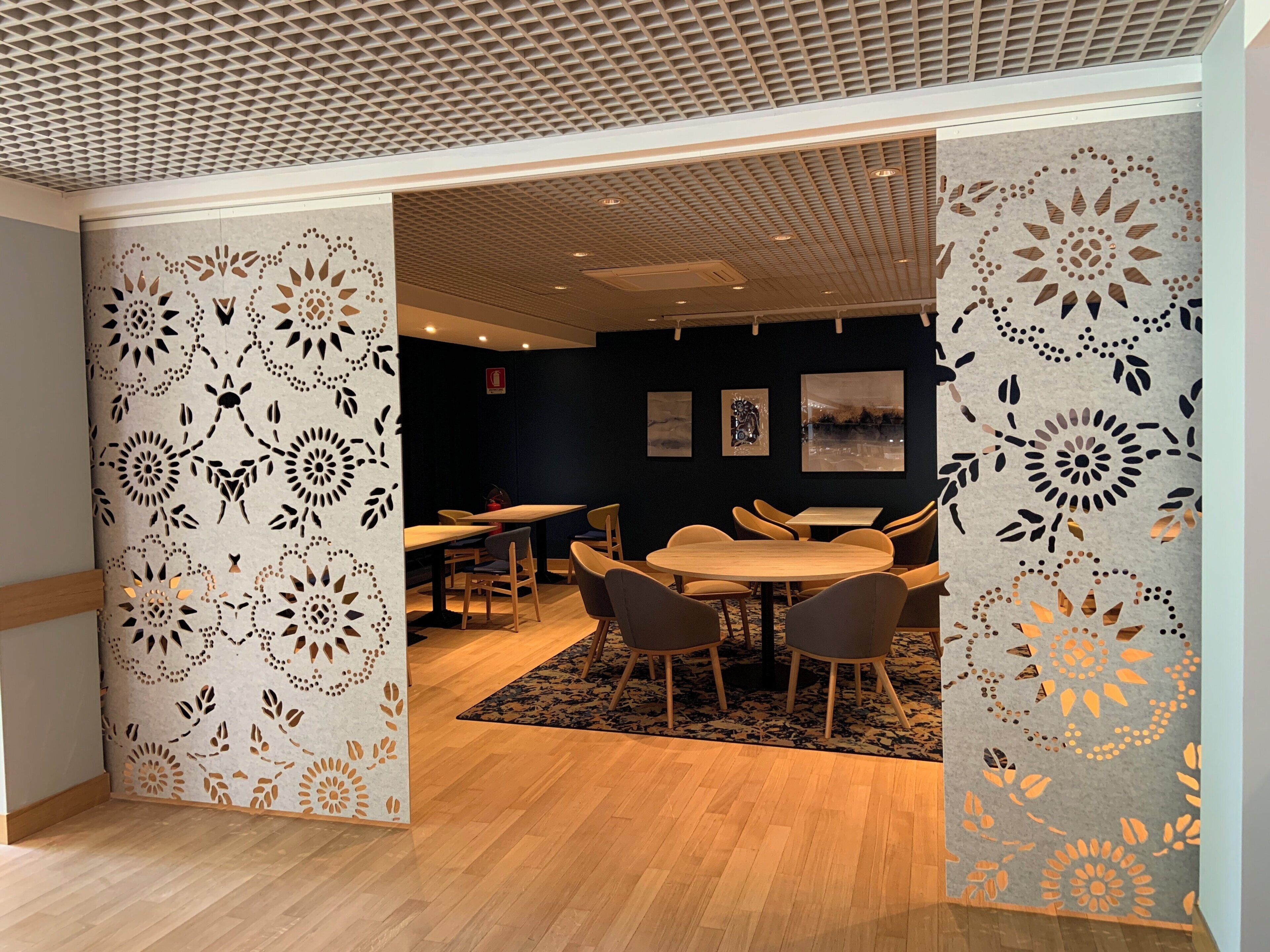 A modern interior with a wooden floor, a round table with chairs, and a patterned wall.