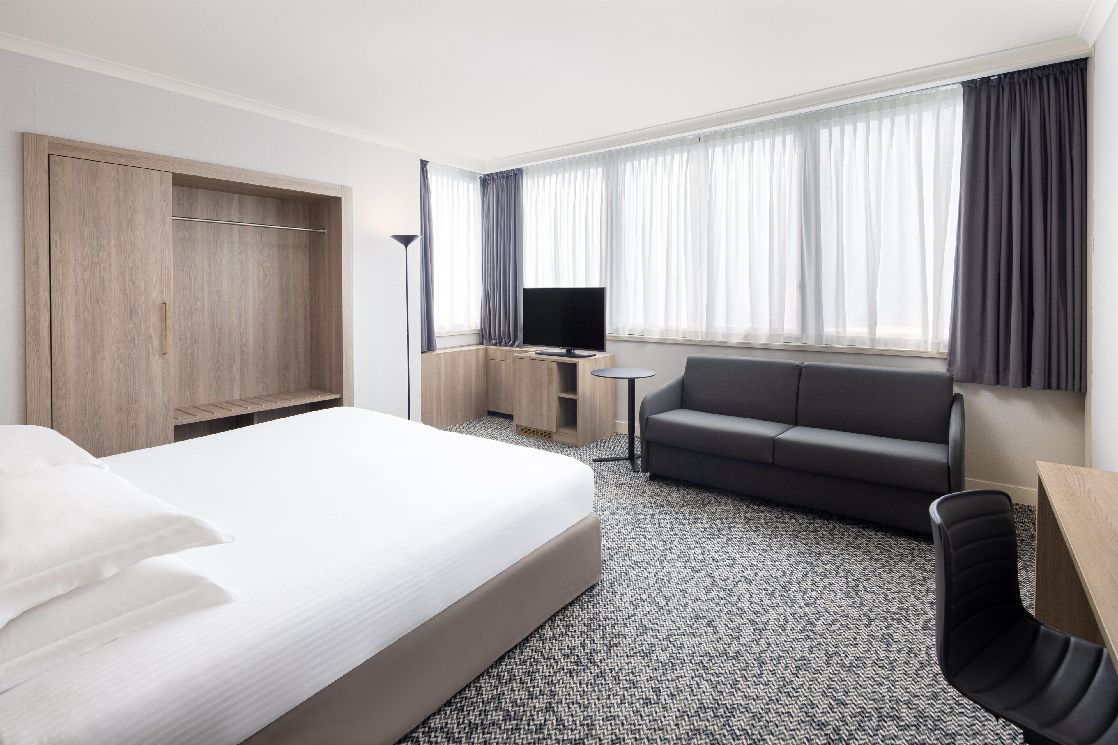 Een hotelkamer met een groot bed, een bank, een televisie en een bureau.