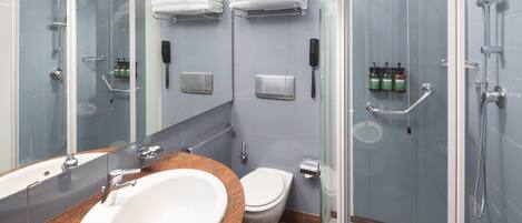Un baño moderno con cabina de ducha de vidrio, un lavabo blanco con encimera de granito, inodoro y un espejo grande.