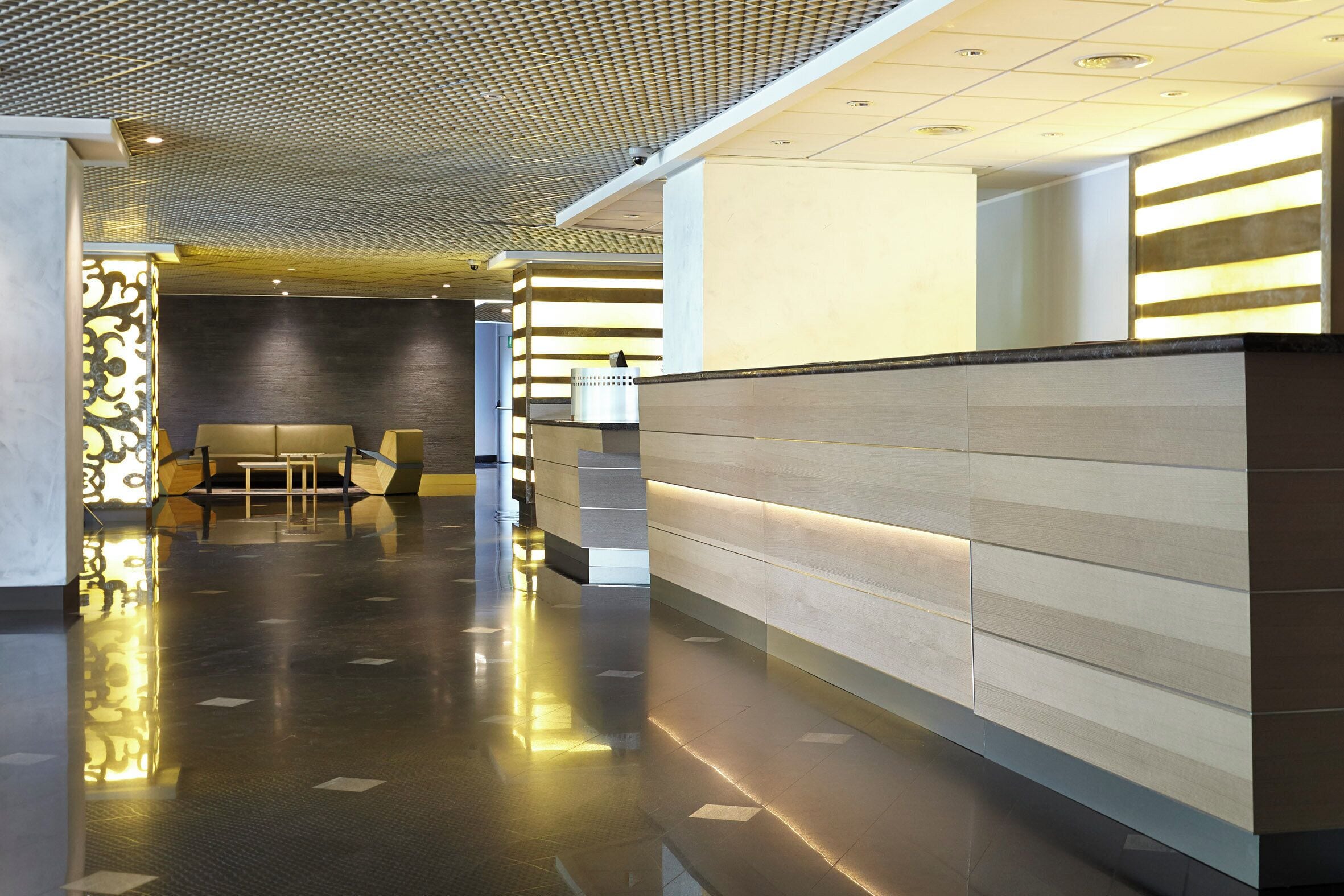 Un hall d’entrée moderne avec un comptoir d’accueil, un espace salon et un plafond orné de motifs.